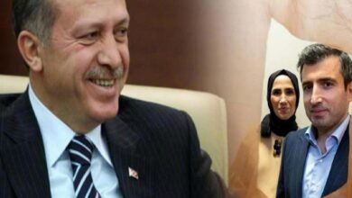 Two men in suits smiling in the foreground, with a woman wearing a headscarf in the background.