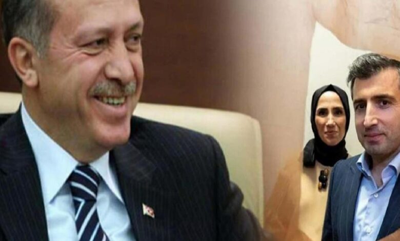 Two men in suits smiling in the foreground, with a woman wearing a headscarf in the background.