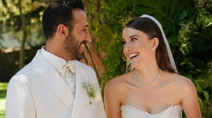 Bride and groom smiling at each other outdoors on their wedding day, greenery in the background.