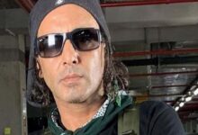 Man wearing a black beanie and sunglasses in an indoor parking garage.