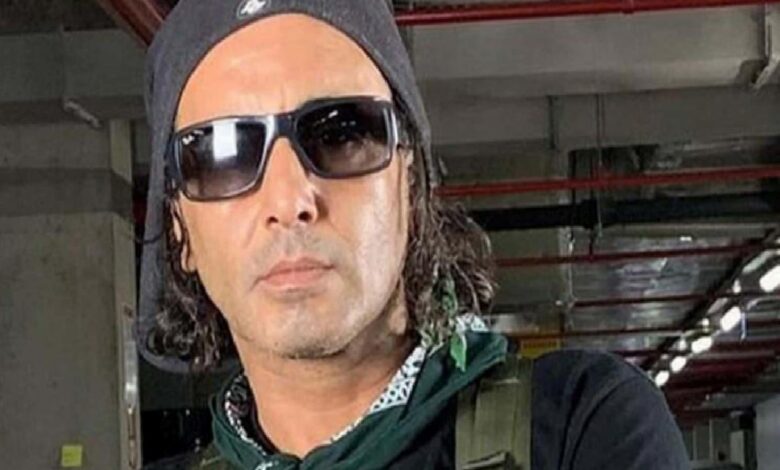 Man wearing a black beanie and sunglasses in an indoor parking garage.