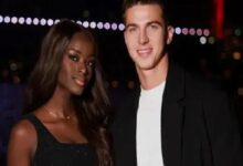 Two people posing for a nighttime photo together; woman in a black dress, man in a black jacket and white shirt, both smiling.