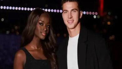 Two people posing for a nighttime photo together; woman in a black dress, man in a black jacket and white shirt, both smiling.
