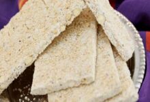 Slices of sesame brittle arranged on a plate, with a purple cloth in the background, showing crunchy textured bars