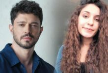 Man with dark hair and stubble in a blue shirt beside a woman with long curly brown hair, both looking at the camera.
