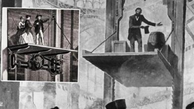 Black-and-white industrial scene with a man on a suspended platform operating a load, while a zoomed inset shows workers near a large pulley mechanism.