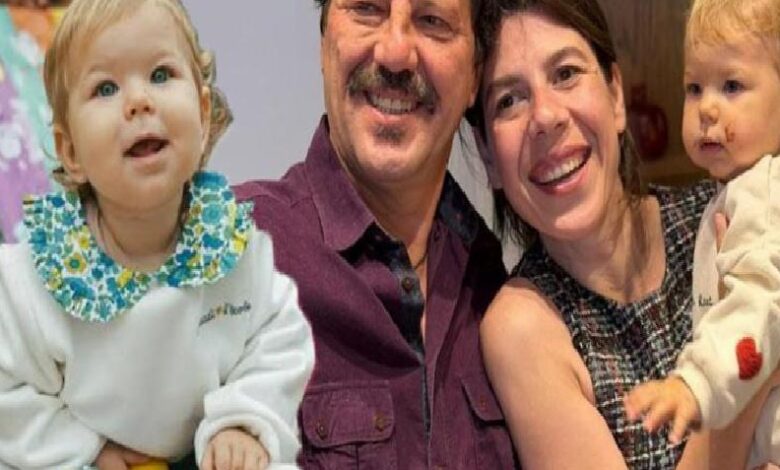 Smiling couple holds two young children for a group photo: girl on the left and a baby on the right.