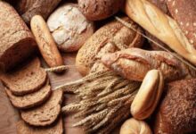 Assorted loaves and slices of crusty bread arranged on a wooden surface.