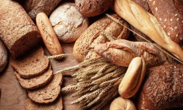 Assorted loaves and slices of crusty bread arranged on a wooden surface.
