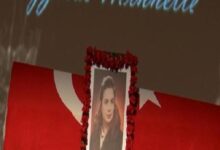 Memorial display with a framed portrait framed by a red flower wreath in front of a red flag backdrop.