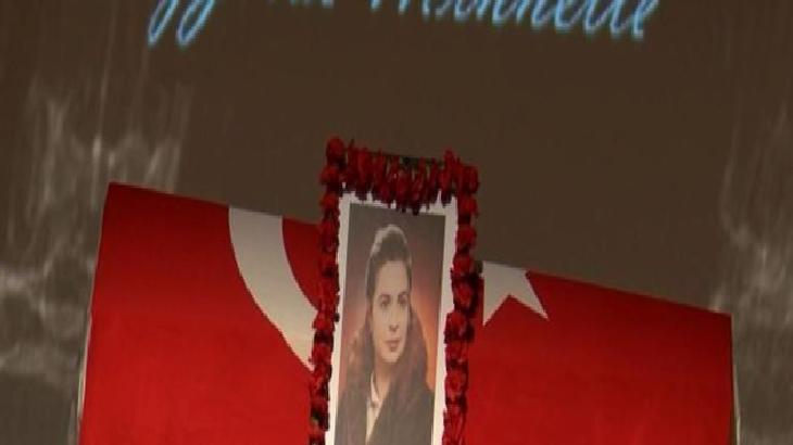 Memorial display with a framed portrait framed by a red flower wreath in front of a red flag backdrop.
