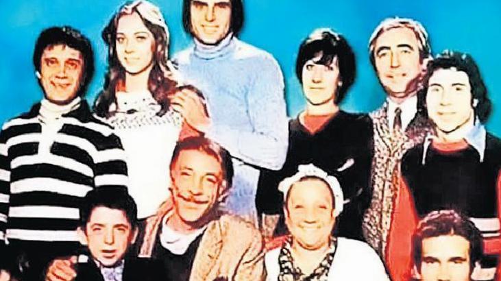 Group portrait of nine people standing together, smiling, in retro clothing against a bright blue backdrop.