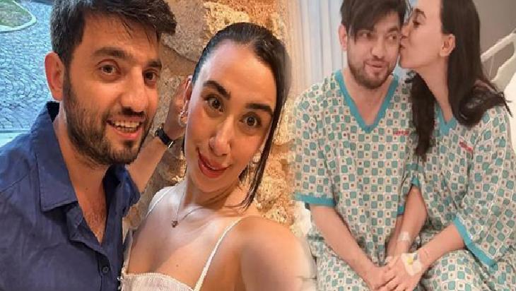 Selfie of a smiling couple in the foreground, casual attire, posing indoors beside a stone wall.