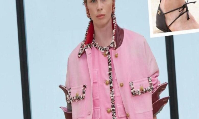Model wearing a pink jacket with black-and-white braided trim and gold buttons; inset shows a black strappy sandal.