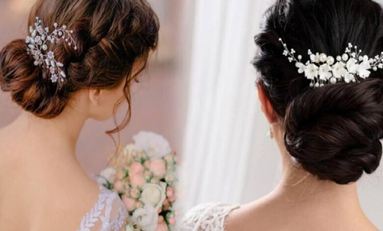 Two brides with elegant updos and delicate white floral hairpieces, one holding a bouquet, seen from behind.