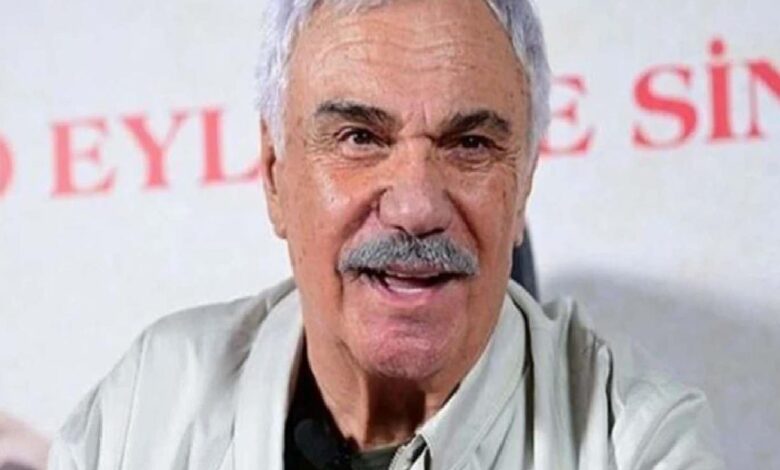Close-up of an older man with gray hair and mustache speaking, wearing a light shirt, with red text in the background.
