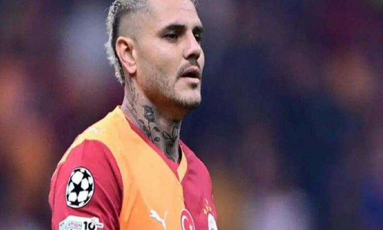 Soccer player with neck tattoos in a red-and-orange jersey on the field during a match, Champions League patch visible on sleeve.