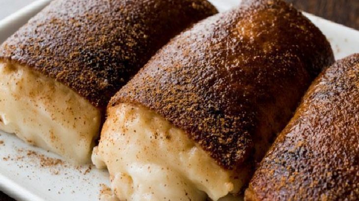 Three cinnamon-sugar coated cream-filled pastries on a plate, with melted vanilla cream oozing from the centers