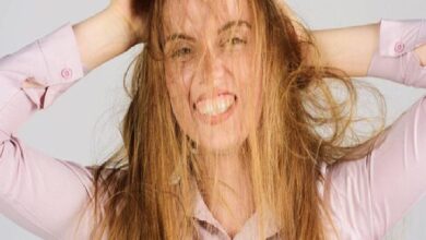 Woman pulling her hair with a strained expression, showing frustration or stress.