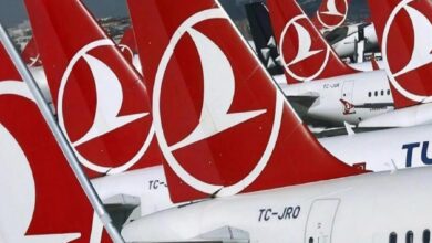 Row of Turkish Airlines airplanes parked at an airport, showing red tails with the white logo lined up on the tarmac Down to Gate area focus on tails