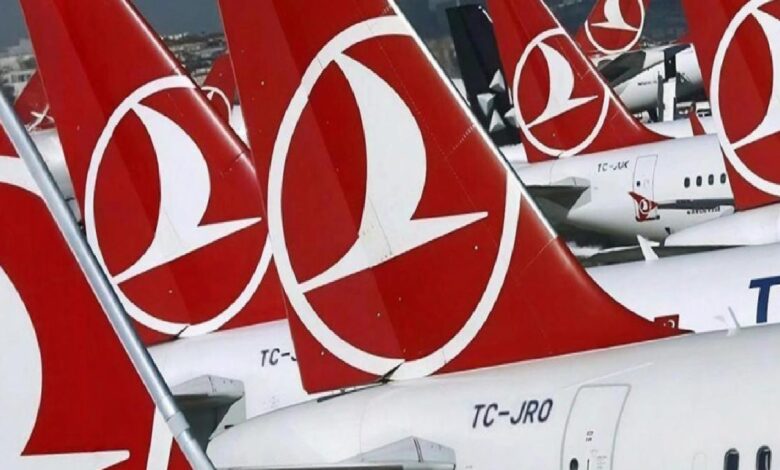 Row of Turkish Airlines airplanes parked at an airport, showing red tails with the white logo lined up on the tarmac Down to Gate area focus on tails