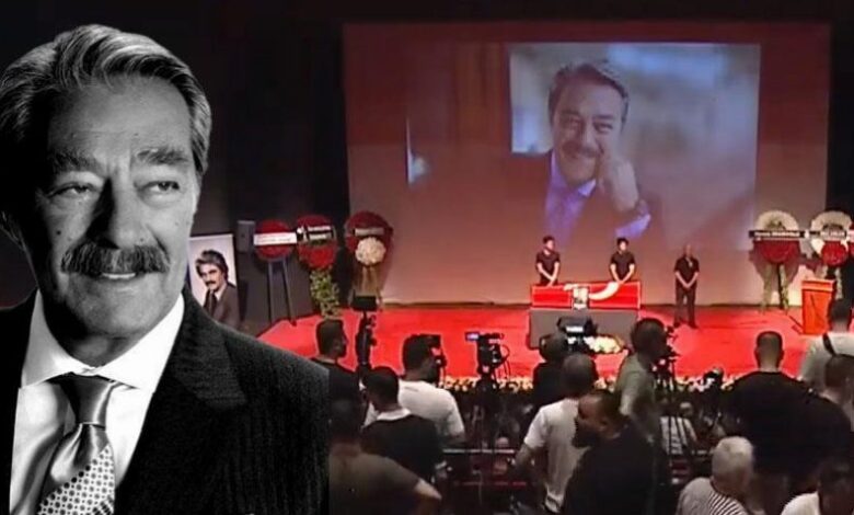 Prominent black-and-white portrait of a suited man overlaid on a conference stage with a large screen showing a smiling man waving to attendees and a crowd watching the event.