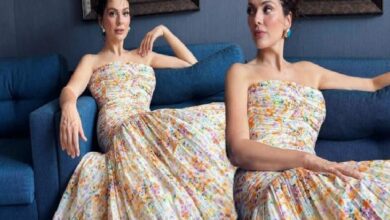 Two women in matching strapless floral dresses sit on a blue sofa, posing gracefully.