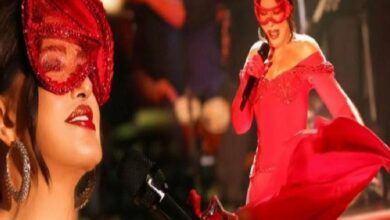 Performer in a red dress and mask singing into a microphone on stage, dramatic scene.