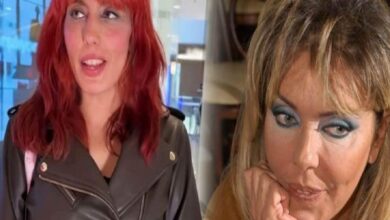 Two women side by side indoors: left has red hair and a black leather jacket, looking upward; right has heavy blue eye makeup, resting her chin on her hand.