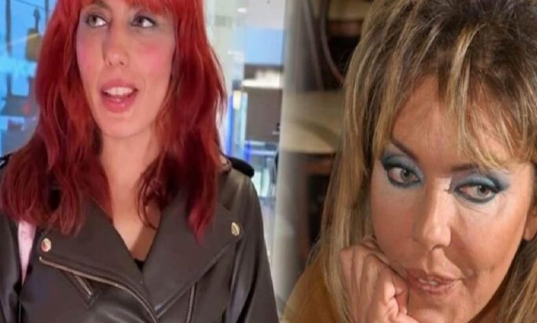 Two women side by side indoors: left has red hair and a black leather jacket, looking upward; right has heavy blue eye makeup, resting her chin on her hand.
