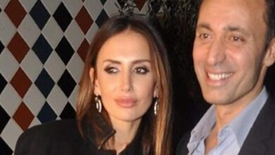 A man and a woman smile for a photo at a social event, with a diamond-pattern wall in the background.