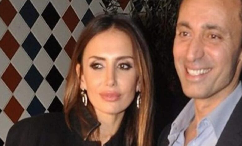 A man and a woman smile for a photo at a social event, with a diamond-pattern wall in the background.