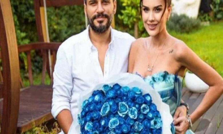 A couple outdoors posing with a large bouquet of blue roses.
