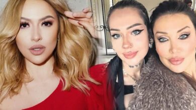 Three women posing for a close-up selfie indoors: a blonde in a red top on the left, and two women with dark hair and bold makeup on the right.